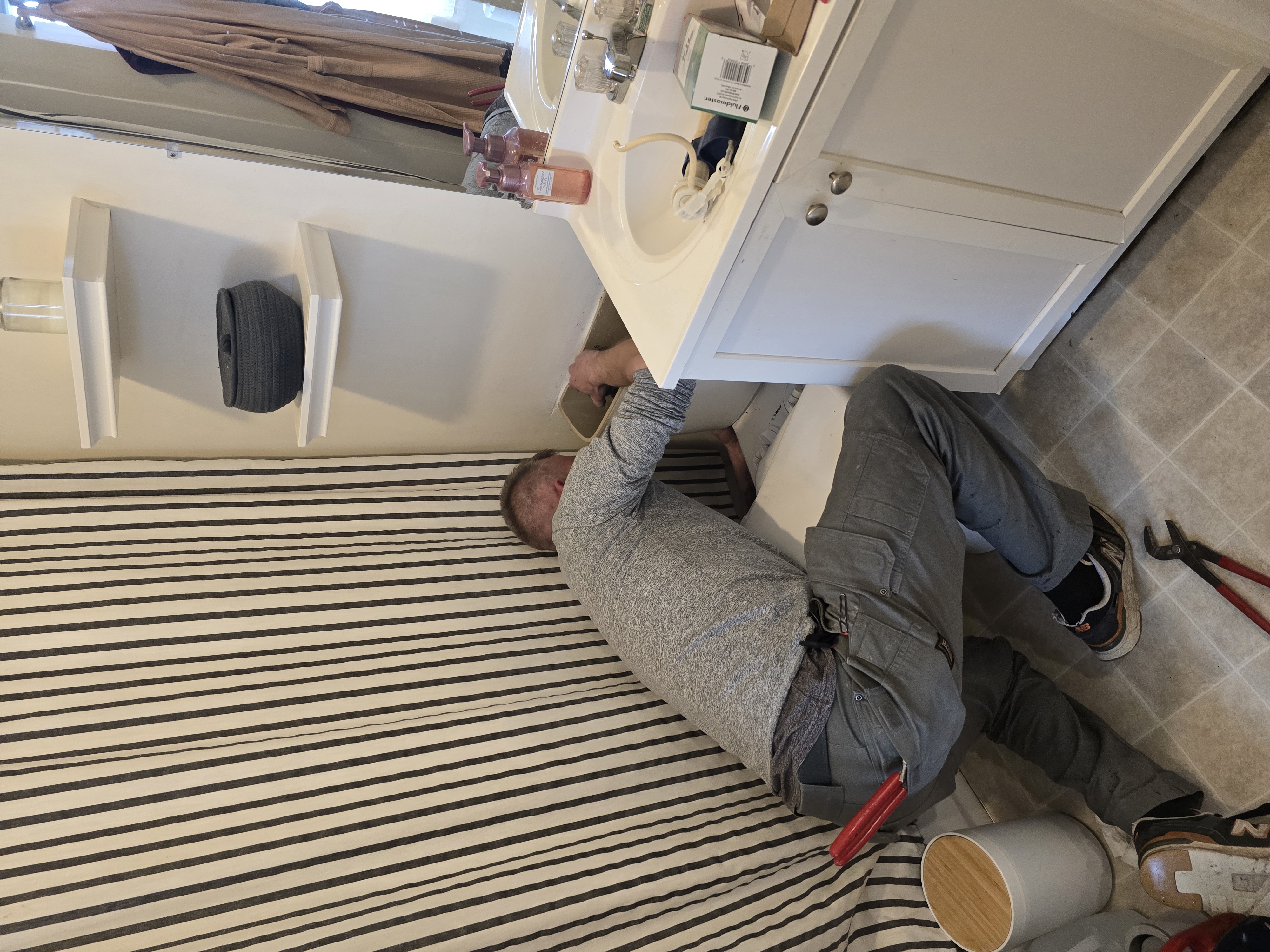 Plumber servicing a bathroom vanity sink